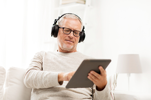 technology, people, lifestyle and distance learning concept - happy senior man with tablet pc computer and headphones listening to music at home