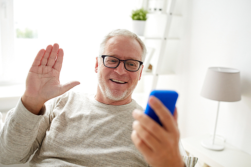 technology, people, lifestyle and communication concept - happy senior man with smartphone having video call and waving hand at home