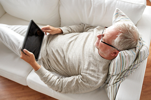 technology, people and lifestyle concept - senior man with black blank tablet pc computer screen lying on sofa at home
