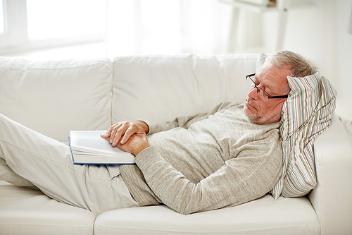 old age, rest and people concept - senior man lying on sofa with book and sleeping at home