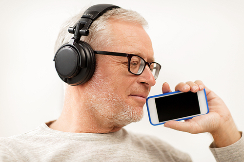 technology, people, lifestyle and distance learning concept - happy senior man with smartphone and headphones listening to music and singing at home