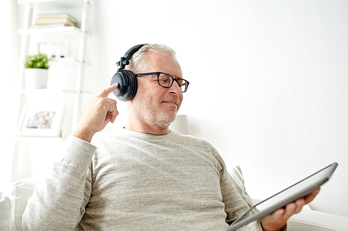 technology, old people, lifestyle and distance learning concept - happy senior man with tablet pc computer and headphones listening to music at home