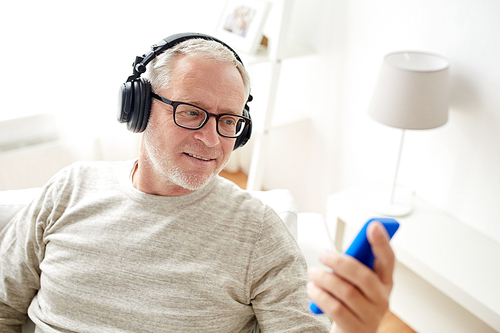 technology, people, lifestyle and distance learning concept - happy senior man with smartphone and headphones listening to music at home