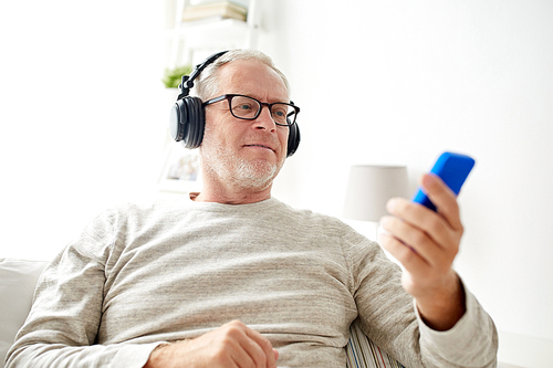 technology, people, lifestyle and leisure concept - happy senior man with smartphone and headphones listening to music at home