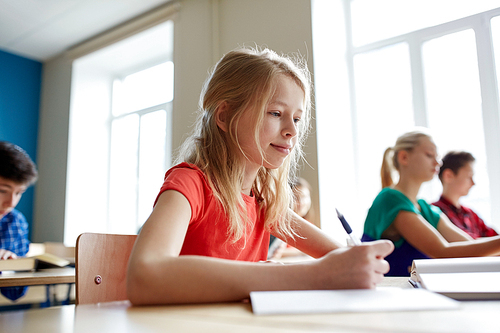 education, learning and people concept - student girl with book writing school test