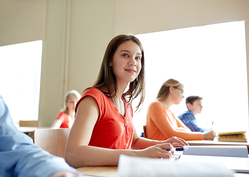 education, learning and people concept - happy student girl with book writing school test