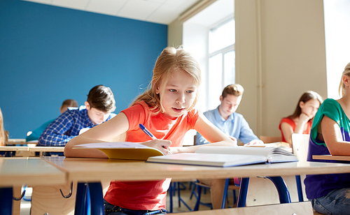 education, learning and people concept - student girl with book writing school test