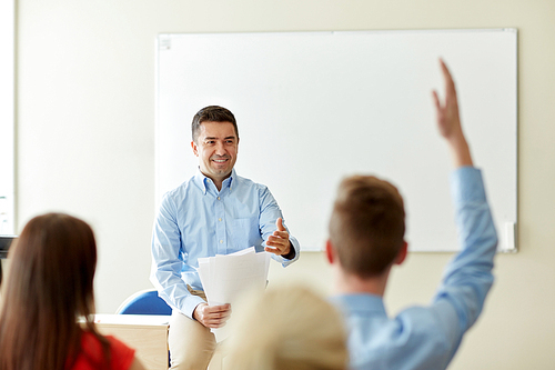 education, school and people concept - group of happy students and teacher with papers or tests