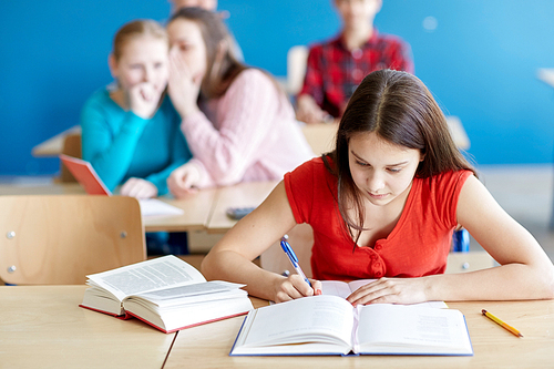 education, bullying, social relations and people concept - students gossiping behind classmate back at school