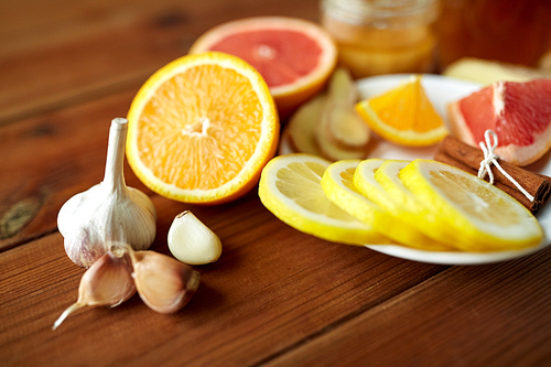 health, traditional medicine and ethnoscience concept - garlic, lemon, orange and other folk remedy on wooden background