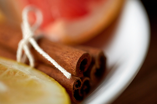 cooking, spice and ethnoscience concept - close up of cinnamon on plate