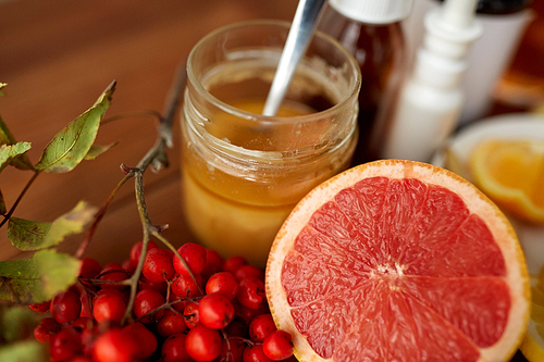 healthcare, traditional medicine and ethnoscience concept - grapefruit, honey with rowanberry and drugs