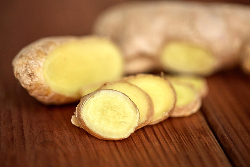 ethno science, culinary, diet,  food and objects concept - close up of ginger root on wooden table