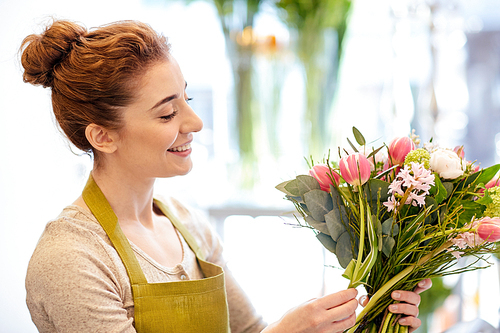 people, business,  and floristry concept - happy smiling florist woman making bunch at flower shop