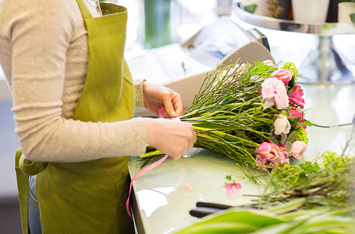 people, business,  and floristry concept - close up of florist woman making bunch at flower shop