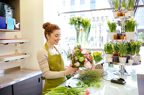 people, business,  and floristry concept - happy smiling florist woman making bunch at flower shop