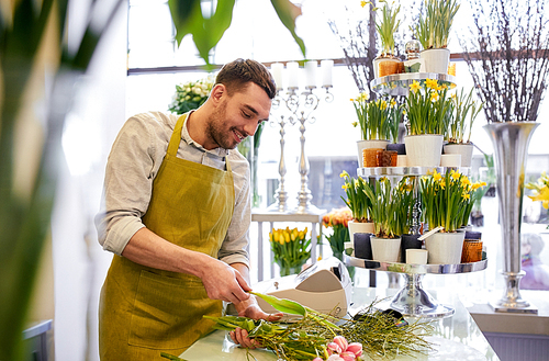 people, business,  and floristry concept - happy smiling florist man making bunch at flower shop