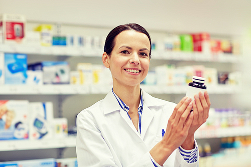 medicine, pharmaceutics, health care and people concept - happy female pharmacist with drug jar at pharmacy