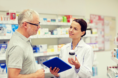 medicine, pharmaceutics, health care and people concept - happy pharmacist with tablet pc computer showing drug to senior man customer at drugstore