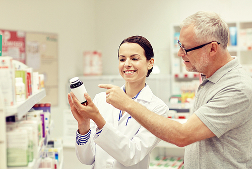 medicine, pharmaceutics, health care and people concept - happy pharmacist showing drug to senior man customer at drugstore