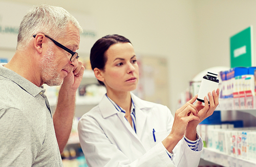 medicine, pharmaceutics, health care and people concept - pharmacist showing drug to senior man customer at drugstore