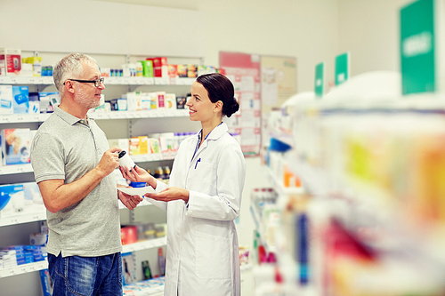 medicine, pharmaceutics, health care and people concept - happy pharmacist giving drug to senior man customer and taking prescription at drugstore