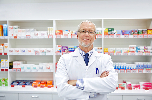 medicine, pharmacy, people, health care and pharmacology concept - smiling senior male pharmacist in white coat at drugstore