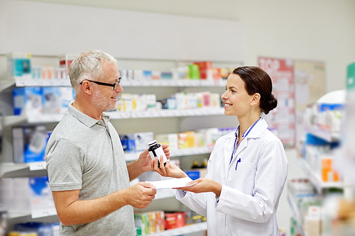 medicine, pharmaceutics, health care and people concept - happy pharmacist giving drug to senior man customer and taking prescription at drugstore