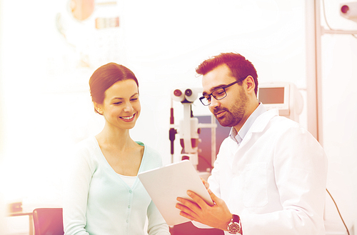 health care, medicine, people, eyesight and technology concept - optician in glasses with tablet pc computer and patient at eye clinic or optics store