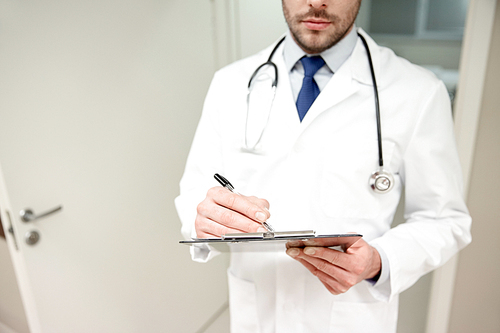 medicine, healthcare, profession and people concept - close up of male doctor with clipboard and stethoscope at hospital