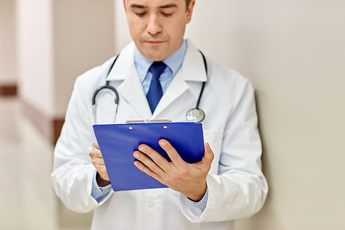 medicine, healthcare, profession and people concept - close up of male doctor with clipboard at hospital
