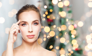 beauty, people, holidays and plastic surgery concept - beautiful young woman showing her forehead over christmas tree lights background