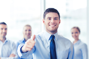 business, people and teamwork concept - smiling businessman showing thumbs up with group of businesspeople in office