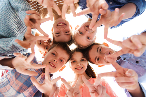 childhood, fashion, friendship and people concept - happy smiling children showing peace hand sign and standing in circle