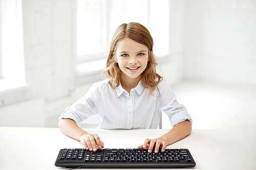 education, children, technology and people concept - little student girl with computer keyboard at school