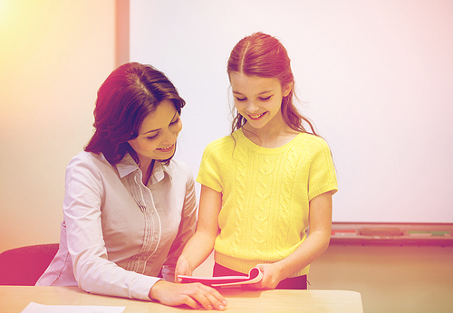 education, elementary school, learning, examination and people concept - school girl with notebook and teacher in classroom