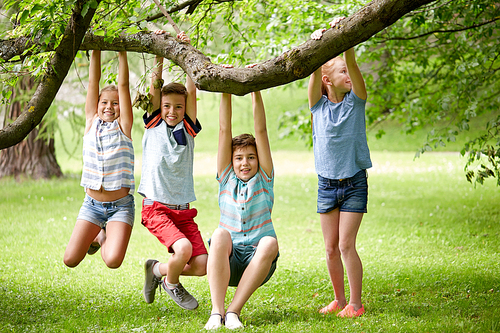 friendship, childhood, leisure and people concept - group of happy kids or friends hanging on tree and having fun in summer park