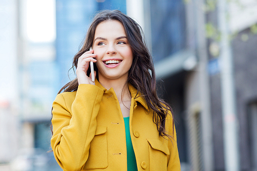 technology, communication and people concept - smiling young woman or girl calling on smartphone on city street