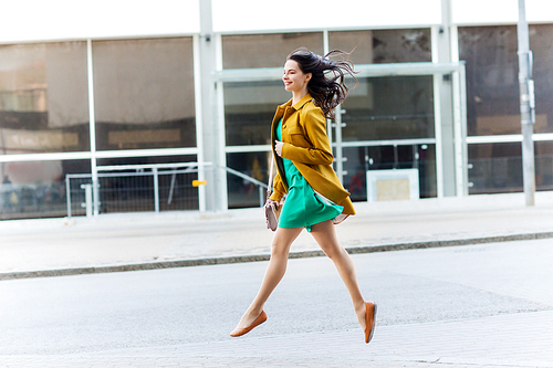 fashion and people concept - happy young woman or teenage girl running and jumping high on city street