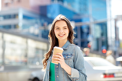 drinks and people concept - happy young woman or teenage girl drinking coffee from paper cup on city street