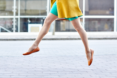 fashion and people concept - happy young woman or teenage girl legs flying above pavement on city street