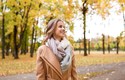 season and people concept - beautiful happy young woman walking in autumn park