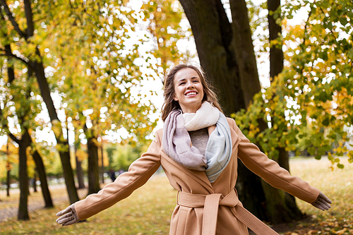 season and people concept - beautiful happy young woman walking in autumn park