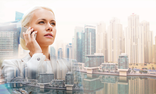 business, technology, communication and people concept - serious businesswoman with smartphone talking over dubai city background with double exposure effect