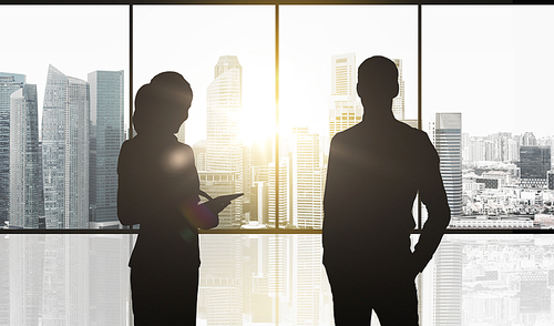 business, partnership, teamwork and people concept - silhouettes of partners over office window and singapore city skyscrapers background and sun light
