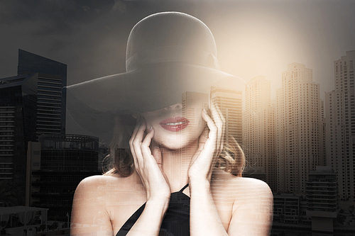people, luxury and fashion concept - beautiful woman in black hat over dubai city with double exposure background