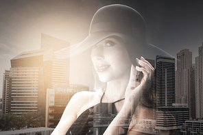 people, luxury and fashion concept - beautiful woman in black hat over dubai city with double exposure background