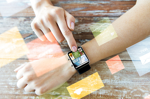 business, modern technology, media, internet and people concept - close up of female hands setting smart watch with news web page on screen on wooden table