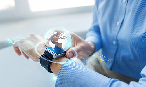 business, technology, network, communication and people concept - close up of woman hands setting smart watch with earth globe hologram at office