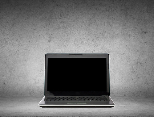 technology and advertisement concept - laptop computer with black blank screen over gray concrete background